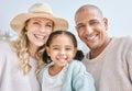 Portrait of an interracial happy family bonding while on a beach vacation together. Cute little girl embracing and