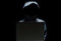 Portrait of Invisible man in the hood on black background. Hacker with laptop Royalty Free Stock Photo