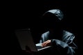 Portrait of Invisible man in the hood on black background. Hacker with laptop Royalty Free Stock Photo