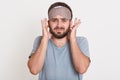 Portrait of irritated angry young man having beard, looking directly at camera, covering his ears with fingers, wearing t shirt Royalty Free Stock Photo
