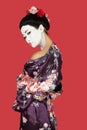 Portrait of Japanese woman in kimono standing over red background