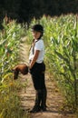 Portrait of a jockey girl in a helmet and a white t-shirt, who sits on a brown toy horse in a corn field Royalty Free Stock Photo