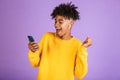 Portrait of joyful african american man smiling and holding smartphone, while listening to music via bluetooth earpod, isolated o