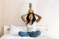 Portrait of joyful African girl with golden eye patches on her face, carries pineapple on head, looking at camera and Royalty Free Stock Photo