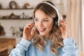 Portrait of joyful blond girl 20s wearing headphones listening to music at home Royalty Free Stock Photo