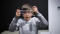 portrait of a joyful boy waving at the camera and playing with a cylindrical lens, distorting the display of the eyes