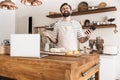 Portrait of joyful brunette man using smartphone while making homemade pasta in kitchen at home Royalty Free Stock Photo