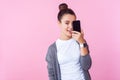 Portrait of joyful brunette teen girl smiling and covering half face with cell phone. isolated on pink background Royalty Free Stock Photo