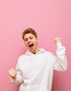 Portrait of a joyful guy in light casual clothing rejoices in victory over a pink background, looks into the camera and smiles Royalty Free Stock Photo
