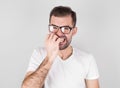 Portrait of joyful handsome bearded guy clenches teeth, blinks eye, bites nails over gray background