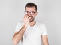 Portrait of joyful handsome bearded guy clenches teeth blinks eye bites nails over gray background