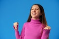 Portrait of a joyful happy teenage girl celebrating success on blue background Royalty Free Stock Photo