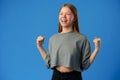 Portrait of a joyful happy teenage girl celebrating success on blue background Royalty Free Stock Photo