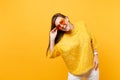 Portrait of joyful happy young woman in fur sweater, white pants holding heart orange glasses stand isolated on bright