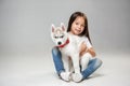 Portrait of a joyful little girl having fun with siberian husky puppy on the floor at studio Royalty Free Stock Photo