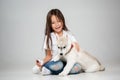 Portrait of a joyful little girl having fun with siberian husky puppy on the floor at studio Royalty Free Stock Photo