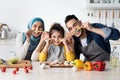 Portrait Of Joyful Muslim Family Of Three Fooling Together In Kitchen