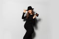 Portrait of joyful pregnant woman, wearing black dress and hat, holding ultrasound scan of her baby. Royalty Free Stock Photo