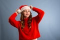 Portrait of joyful pretty woman in red santa claus hat laughing  on gray background. Beautiful girl looking happy and Royalty Free Stock Photo