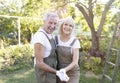 Portrait of joyful senior couple of gardeners in love, wearing aprons and dancing in their garden