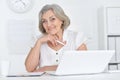 Portrait of joyful senior woman with laptop at home