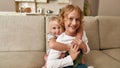 Portrait of joyful siblings, little boy and girl smiling at camera, embracing each other while sitting on a couch at Royalty Free Stock Photo