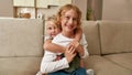 Portrait of joyful siblings, little boy and girl smiling at camera, embracing each other while sitting on a couch at Royalty Free Stock Photo