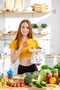 joyful sports woman with lots of healthy fresh food in kitchen. Concept of losing weight, sports and healthy eating