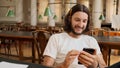 Portrait of joyful student happily using smartphone in library. Handsome guy with phone studying in college Royalty Free Stock Photo