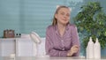 Portrait of a joyful woman sitting at a dressing table in front of a mirror. A woman without makeup, wearing a headband Royalty Free Stock Photo