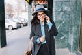 Portrait joyful young business woman walking on street in city, smiling to camera and speaking on phone. Attractive Royalty Free Stock Photo