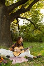 Portrait of joyful young man playing guitar in green park Royalty Free Stock Photo