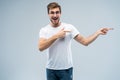Portrait of a joyful young man pointing fingers away at copy space on his palm isolated over gray background. Royalty Free Stock Photo