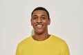 Portrait of joyful young mixed race man in casual yellow t shirt smiling at camera while posing isolated over gray Royalty Free Stock Photo