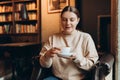 Portrait of joyful young woman enjoying a cup of coffee at home. Smiling pretty girl drinking hot drink in cafe in Royalty Free Stock Photo