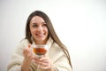 Portrait of joyful young woman enjoying a cup of coffee at home. Smiling pretty girl drinking hot tea in winter. Excited