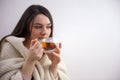 Portrait of joyful young woman enjoying a cup of coffee at home. Smiling pretty girl drinking hot tea in winter. Excited