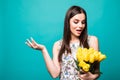 My lovely flowers. Portrait of a joyful young woman in summer dress holding yellow tulips bouquet isolated over blue background Royalty Free Stock Photo