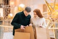 Portrait of joyfulyoung couple walking shopping mall holding shopping bags, looking inside, excited about their new Royalty Free Stock Photo