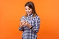 Portrait of joyous beautiful brunette woman with charming smile holding cellphone. indoor studio shot isolated on orange