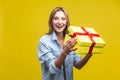 Portrait of joyous beautiful woman in denim shirt standing with opened gift box. studio shot on yellow background