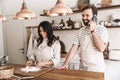 Portrait of joyous couple using smartphone while cooking together in kitchen at home