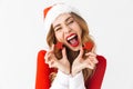 Portrait of joyous woman 20s wearing Santa Claus red costume smiling and holding Christmas decorations, isolated over white Royalty Free Stock Photo