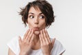 Portrait of joyous woman with short brown hair in basic t-shirt covering her mouth with hands