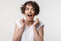 Portrait of joyous woman with short brown hair in basic t-shirt rejoicing and clenching fists Royalty Free Stock Photo