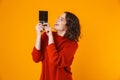 Portrait of joyous woman smiling and holding chocolate bar while standing isolated over yellow background