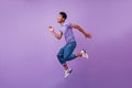 Portrait of jumping amazed guy in white sneakers. Indoor shot of dancing stylish male model in purp