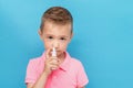 Portrait of a kid with anti-allergic nosal spray on a blue background Royalty Free Stock Photo