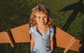 Portrait of kid with backpack wings. Child playing pilot aviator and dreams outdoors in park. Smiling kid dreaming about