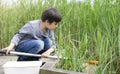 Portrait Kid boy catching creatures in pond with net in summer time,  Child explorer and learning about wild nature in countryside Royalty Free Stock Photo